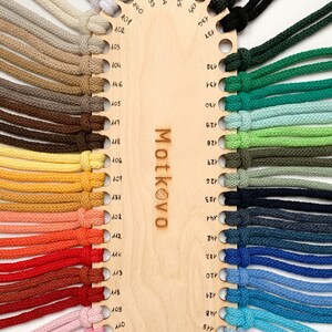 Puede incluir: Una carta de colores de madera muestra una variedad de cordones de colores. Los cordones est&aacute;n dispuestos alrededor del per&iacute;metro de la carta, cada uno con un color diferente, que va desde tonos neutros hasta tonos vibrantes. La palabra "Motkovo" es visible en la carta.