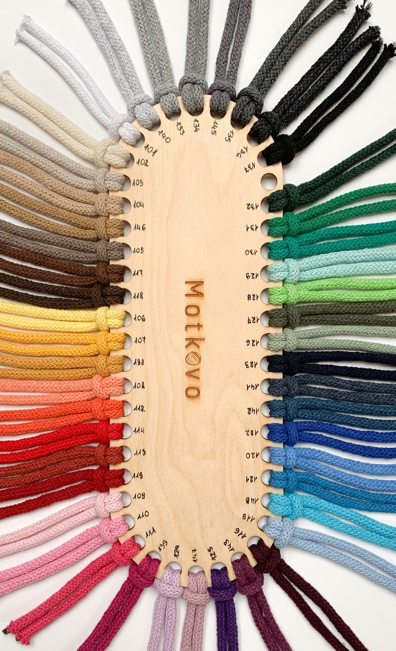 Puede incluir: Una carta de colores de madera muestra una variedad de cordones de colores. Los cordones est&aacute;n dispuestos alrededor del per&iacute;metro de la carta, cada uno con un color diferente, que va desde tonos neutros hasta tonos vibrantes. La palabra "Motkovo" es visible en la carta.