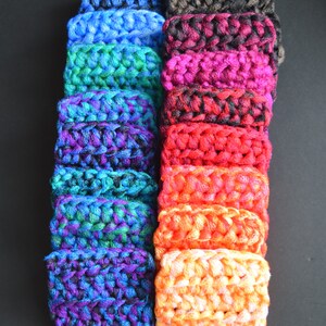 May include: A stack of 16 colorful crocheted squares in various shades of blue, green, purple, red, orange, and brown. The squares are made with a textured yarn and have a slightly fuzzy appearance.