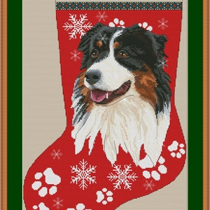May include: A red Christmas stocking with a white border and the word "Aussie" in blue letters. The stocking features a black and brown Australian Shepherd dog with white markings, snowflakes, and white paw prints on a red background.