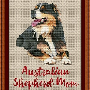 May include: Cross-stitch pattern of an Australian Shepherd dog with a black, brown, and white coat. The dog is sitting with its tongue sticking out. The text "Australian Shepherd Mom" is below the dog.