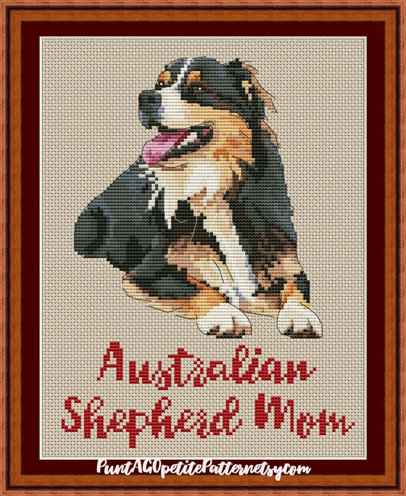 May include: Cross-stitch pattern of an Australian Shepherd dog with a black, brown, and white coat. The dog is sitting with its tongue sticking out. The text "Australian Shepherd Mom" is below the dog.