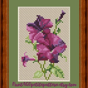 May include: Cross stitch pattern of a purple flower with green leaves. The pattern is on a beige background and is framed in a brown frame.