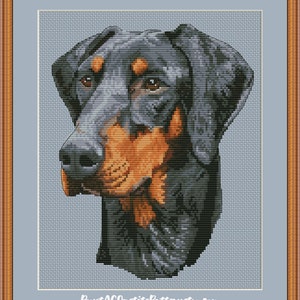 May include: Cross stitch pattern of a black and tan Doberman Pinscher dog's head. The dog is looking to the left of the image. The pattern is on a light blue background.  PuntAGOpatitePatternsEtsy.com