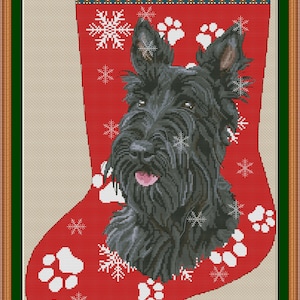 Op de afbeelding: Een rode kerstkous met een kruissteekpatroon van een zwarte Schotse terriër, witte sneeuwvlokken en witte pootafdrukken. De naam SCOTTIE is bovenaan in het zwart geborduurd. De tekst PuntAGOpetitePatternetsy.com staat onderaan.