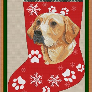 Puede incluir: Una media de Navidad roja con un perro Labrador Retriever blanco asomándose por la parte superior. La media está decorada con copos de nieve blancos y huellas de patas. El texto "LABRADOR" está en la parte superior de la media.