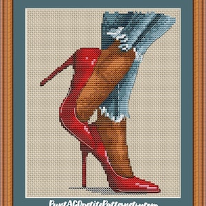 Könnte beinhalten: Kreuzstich-Kunstwerk, das Beine in roten High Heels und blauen Jeans zeigt. Die Absätze sind leuchtend rot mit spitzer Zehenpartie und Stiletto-Absatz. Die Jeans sind hellblau mit ausgefransten Details. Das Kunstwerk ist gerahmt.