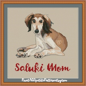 May include: Cross stitch pattern of a brown and white Saluki dog lying down with the text "Saluki Mom" in red below the dog.