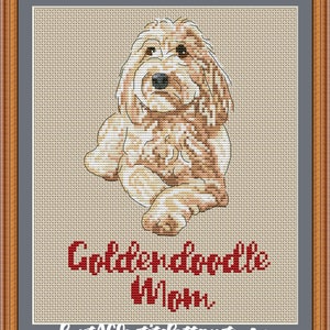 Op de afbeelding: Borduurpatroon van een golden doodle hond die zit met gekruiste poten. De hond is lichtbruin met een witte borst en poten. De tekst "Golden Doodle Mom" staat onder de hond in rood.