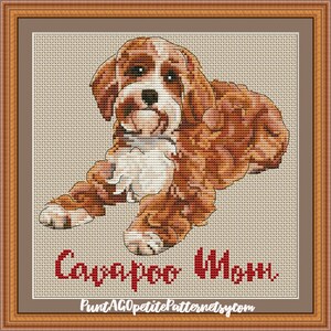 以下が含まれることがあります： 茶色と白の犬のクロスステッチパターン。テキストは「Cavapoo Charm」とウェブサイト「PuntAGOppetitePatternetsy.com」。