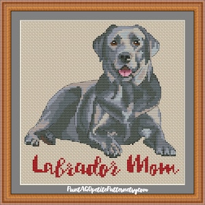 May include: Cross stitch pattern of a black Labrador Retriever dog sitting with its tongue sticking out. The pattern is titled "Labrador's Mom".