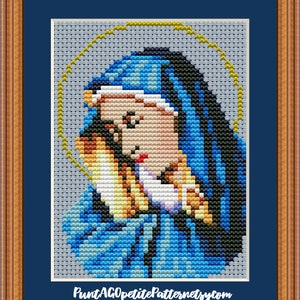 Puede incluir: Un patrón de punto de cruz de la Virgen María sosteniendo al niño Jesús. El patrón está en un esquema de color azul, amarillo y blanco. El patrón está enmarcado en un marco de madera con un passe-partout azul.