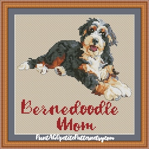 May include: Cross stitch pattern of a Bernedoodle puppy lying down. The puppy is black, brown, and white. The pattern is titled "Bernedoodle Max" and includes the website "PuntAGOpetitePatternetsy.com".