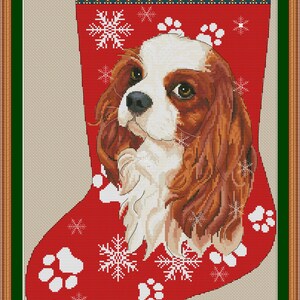 May include: A red Christmas stocking with a white Cavalier King Charles Spaniel dog face and snowflakes. The stocking has the word "CAVALIER" at the top.