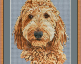 May include: Cross stitch pattern of a golden doodle dog with brown eyes. The dog is looking directly at the viewer. The pattern is available for download on Etsy.