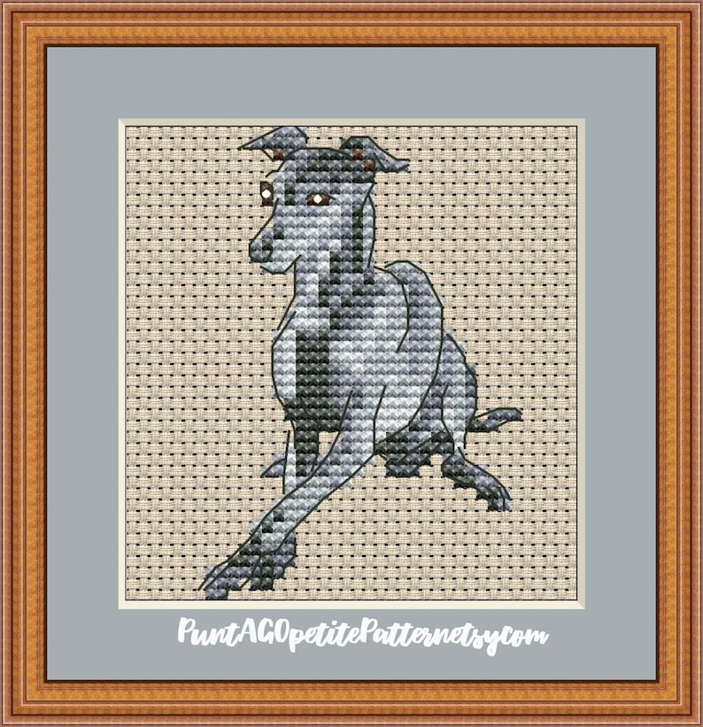 Puede incluir: Arte de punto de cruz de un galgo en tonos grises, negros y blancos. El perro est&aacute; representado en posici&oacute;n sentada, con las patas extendidas. La obra est&aacute; enmarcada en un marco de madera con un passe-partout gris.