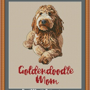 Op de afbeelding: Borduurpatroon van een bruine en witte Golden doodle hond die zit met de tekst "Golden doodle Mom" eronder.