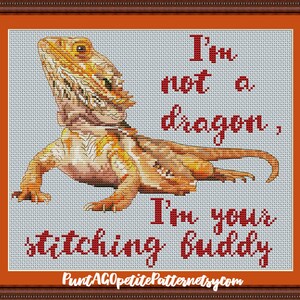 May include: Cross stitch pattern featuring a bearded dragon with the text "I'm not a dragon, I'm your stitching buddy".