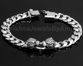 May include: A silver bracelet with a curb chain design. The bracelet features two detailed leopard head accents and a secure clasp. The text "KrishnaJewelsByAnu" is visible on the bracelet.