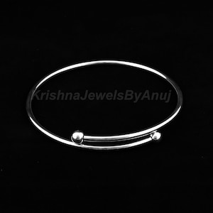 May include: A silver bangle bracelet with two small round balls on the ends.