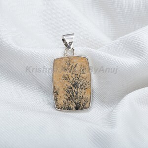 May include: A silver pendant featuring a rectangular, light brown stone with a black dendritic agate tree pattern.