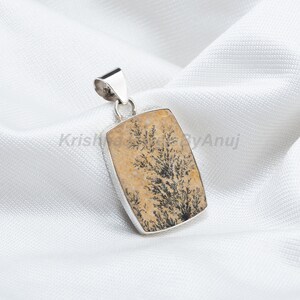 May include: A silver pendant featuring a rectangular piece of dendritic agate with a brown and black tree-like pattern.