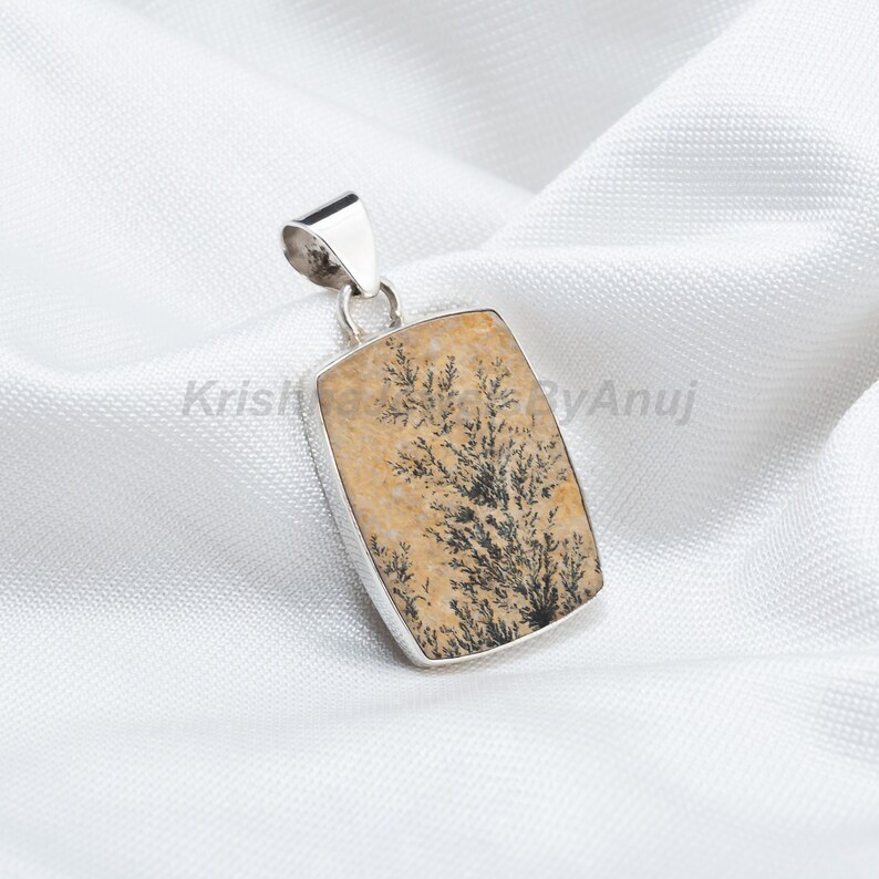 May include: A silver pendant featuring a rectangular piece of dendritic agate with a brown and black tree-like pattern.