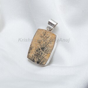 May include: A silver pendant featuring a rectangular stone with a dendritic agate pattern. The stone is a light brown color with black dendritic patterns.