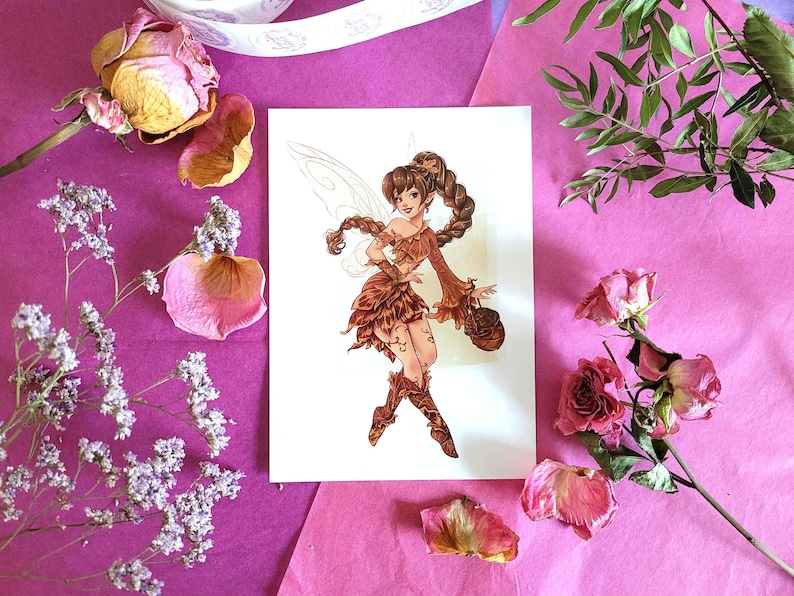 Peut inclure: Illustration d&eacute;taill&eacute;e d'une f&eacute;e aux cheveux bruns et aux ailes, v&ecirc;tue d'une tenue marron, tenant un petit sac. L'&oelig;uvre d'art est sur une carte blanche, entour&eacute;e de roses s&eacute;ch&eacute;es, de p&eacute;tales et de verdure sur fond rose.