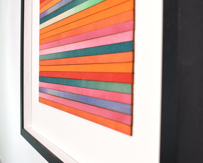 May include: A framed abstract art piece with horizontal stripes of various colors, including orange, pink, blue, and green.