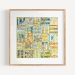 Könnte beinhalten: Ein gerahmtes Kunstwerk mit einem Patchwork-Design aus farbenfrohen Kartenfragmenten. Das Kunstwerk besteht aus quadratischen Blöcken, jeder mit einer einzigartigen Kombination aus Farben und Mustern, darunter Blau-, Gelb- und Orangetöne. Der Rahmen ist aus hellem Holz.