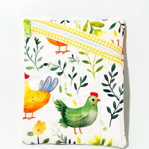 May include: A white quilted pouch featuring a colorful chicken and foliage pattern. The design includes a yellow, orange, and green chicken, with a green zipper and a yellow gingham trim. The pouch is rectangular and has a vertical orientation.