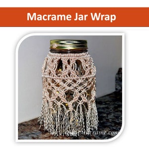 May include: A beige macrame jar wrap with a fringe around the bottom. The jar wrap is made with a knotting technique and is a decorative way to cover a glass jar.