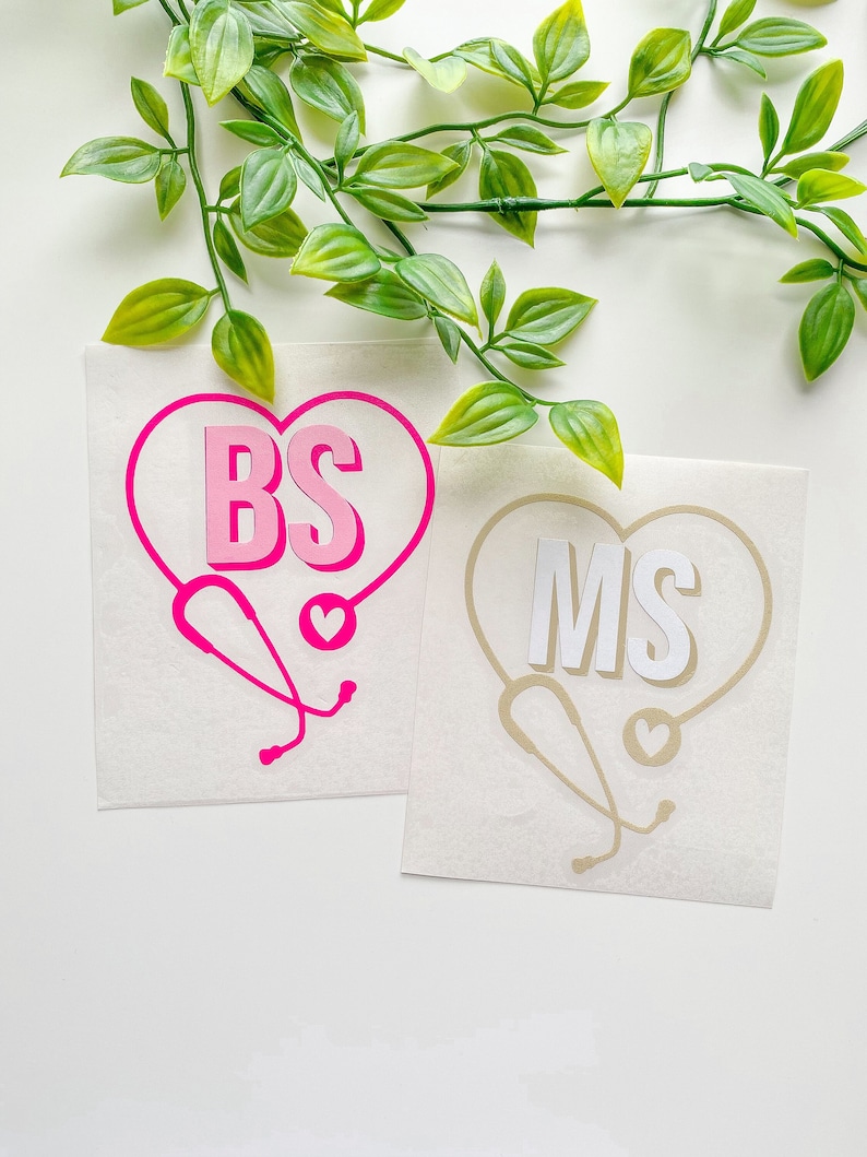 Peut inclure: Deux autocollants en vinyle avec un st&eacute;thoscope et un c&oelig;ur. L'autocollant de gauche est rose avec les lettres "BS" &agrave; l'int&eacute;rieur du c&oelig;ur. L'autocollant de droite est beige avec les lettres "MS" &agrave; l'int&eacute;rieur du c&oelig;ur.