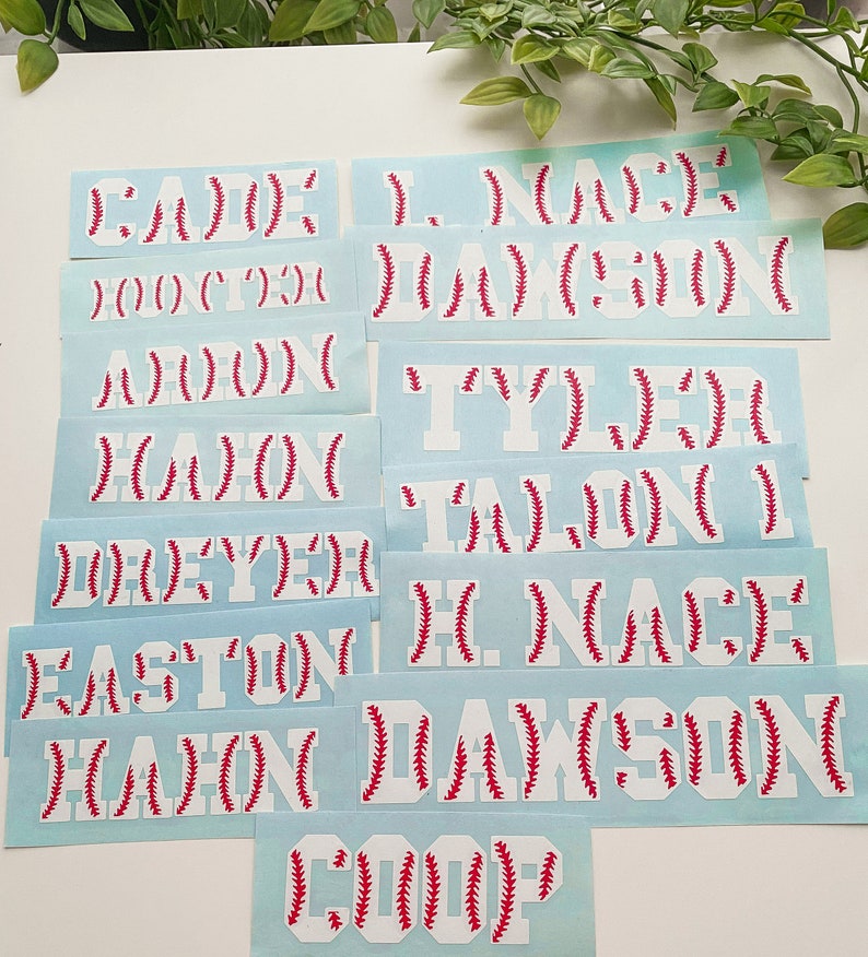 May include: A set of 10 white vinyl baseball-themed name decals with red stitching. The names include: Cade, Hunter, Aaron, Kason, Dreyer, Easton, Kason, Coop, L. Nace Dawson, Tyler, Talon, H. Nace Dawson.