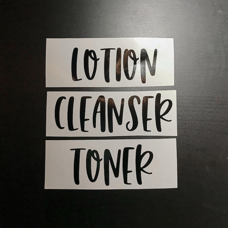May include: Three rectangular white vinyl labels featuring black lettering in a script font. The labels display the words LOTION, CLEANSER, and TONER, each on a separate strip, designed for application onto skincare containers or bathroom bottles.