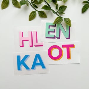May include: A set of rectangular stickers featuring bold, block-style letters. The stickers display the characters HL, EN, KA, and OT in vibrant colors including pink, mint green, blue, and magenta, each with a distinct drop shadow effect.