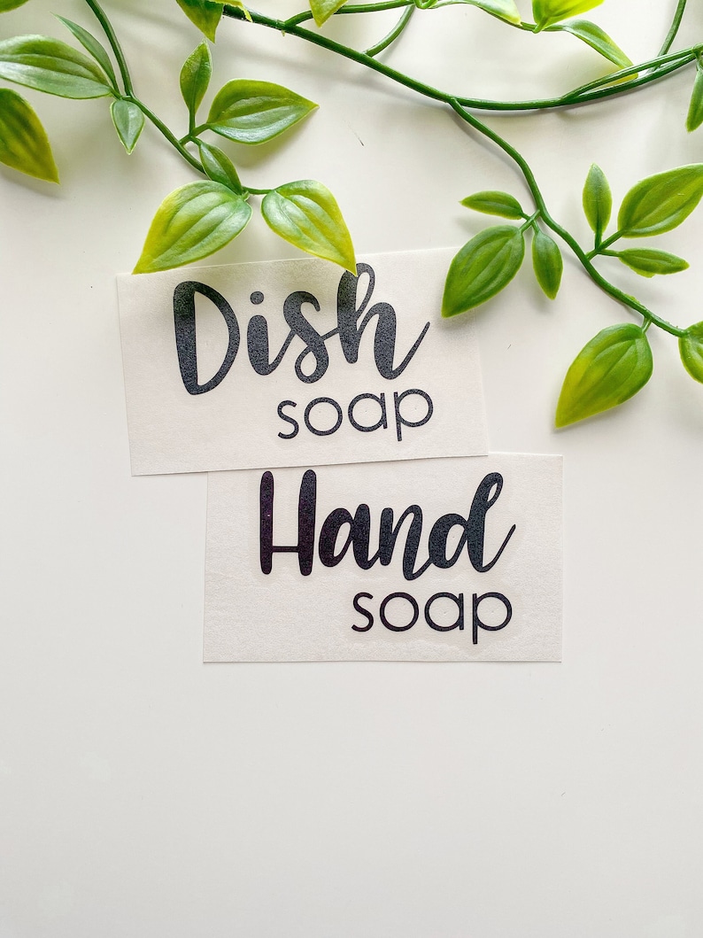 May include: Two rectangular adhesive labels with black lettering on a white background. The top label features the text Dish soap in a combination of script and sans-serif fonts. The bottom label features the text Hand soap in the same font style.