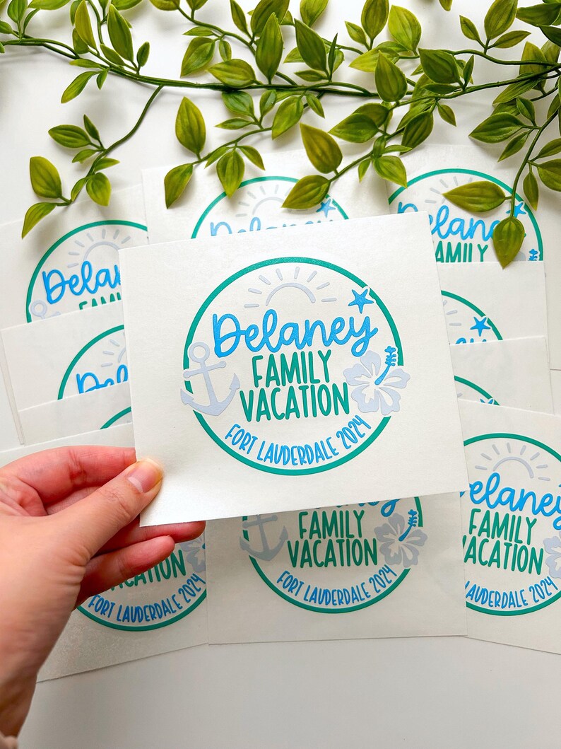 Puede incluir: Una tarjeta cuadrada blanca con un gr&aacute;fico circular que contiene el texto Delaney FAMILY VACATION FORT LAUDERDALE 2024. El dise&ntilde;o incluye un ancla azul claro, un sol, una estrella de mar y una flor de hibisco en tonos azules y verde azulado.