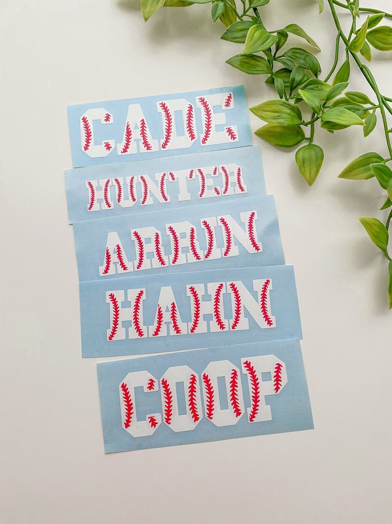 May include: Five white vinyl stickers with baseball stitching in red. The stickers are for names: Cade, Hunter, Aaron, Hahn, and Coop.