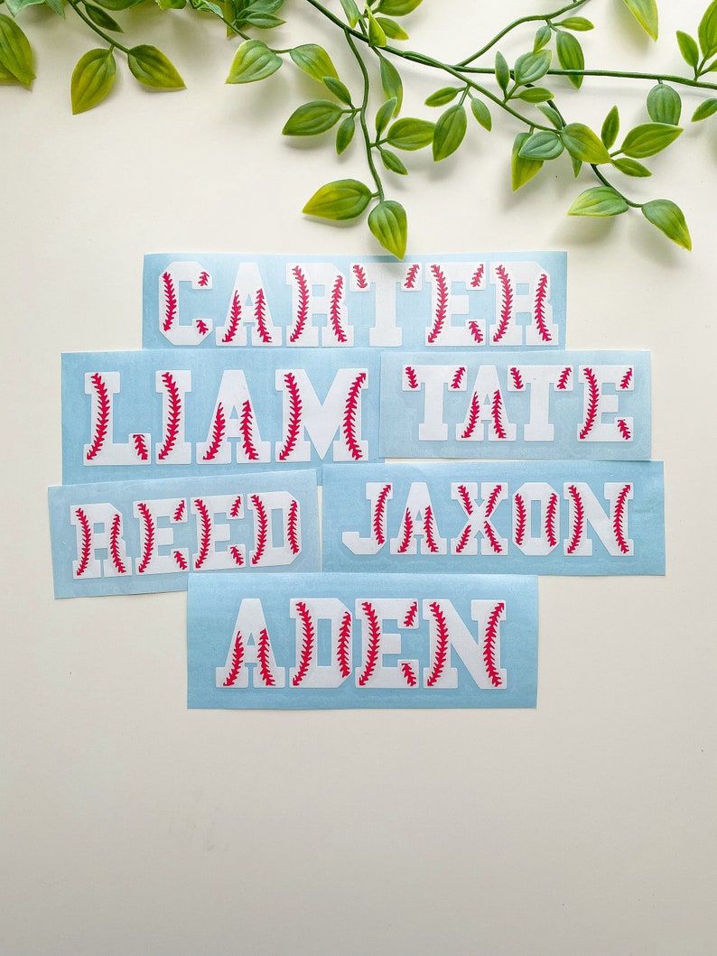 May include: Five white vinyl stickers with red baseball stitching. The stickers are for names: Carter, Liam, Tate, Reed, Jaxon, and Aden.