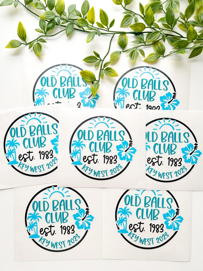 Puede incluir: Una colecci&oacute;n de pegatinas circulares de vinilo con un borde negro. El texto OLD BALLS CLUB, est. 1983 y KEY WEST 2023 aparece en azul brillante. El dise&ntilde;o incluye un sol azul, dos palmeras y un gr&aacute;fico de una flor de hibisco.