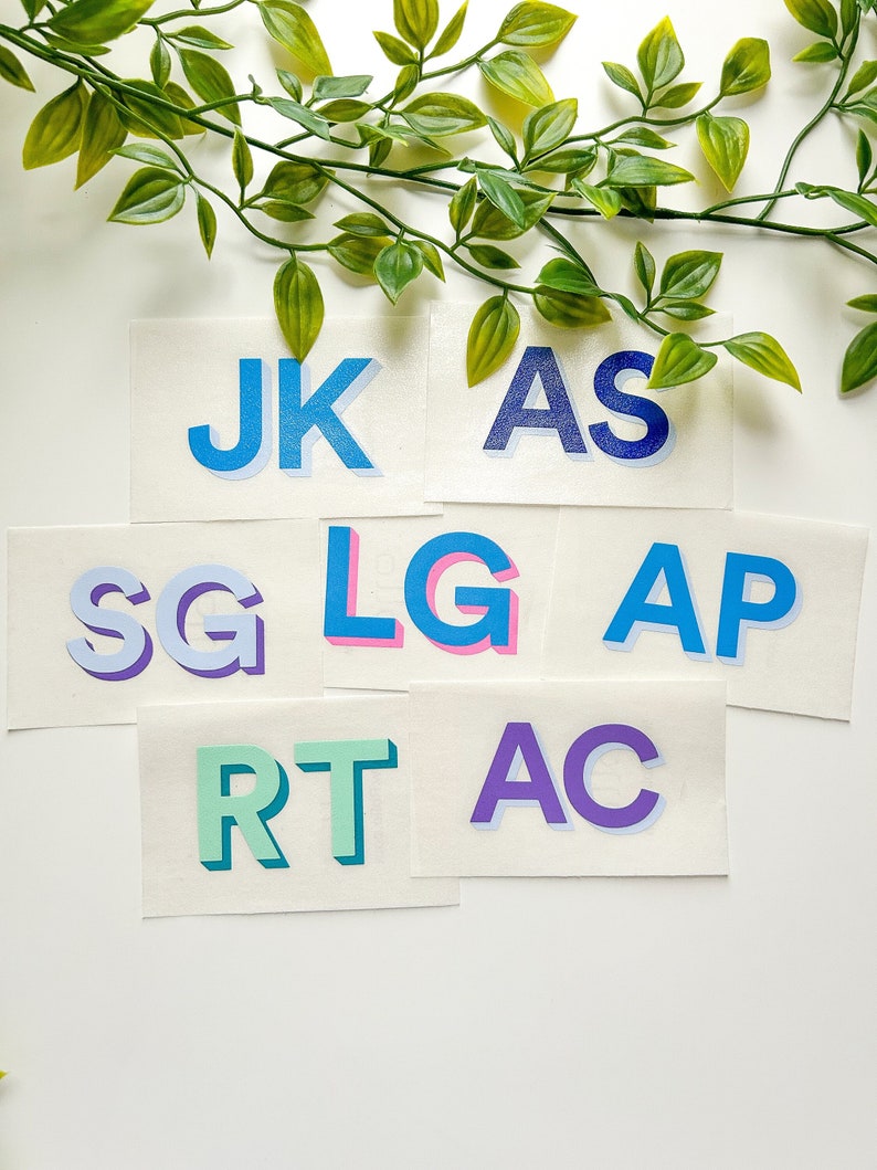 May include: A collection of seven rectangular stickers featuring two-letter combinations JK, AS, SG, LG, AP, RT, and AC. Each sticker displays bold, sans-serif capital letters in various colors including blue, purple, pink, and green with drop shadows.