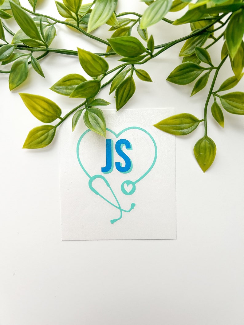 Peut inclure: Une carte blanche avec un st&eacute;thoscope et un c&oelig;ur bleus et turquoise. Les initiales "JS" sont dans un c&oelig;ur bleu.