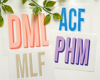 May include: Four rectangular white vinyl decals featuring three-letter monograms in a bold, sans-serif font with a 3D drop shadow effect. The monograms are DML in coral, ACF in bright blue, PHM in purple, and MLF in a neutral beige color.