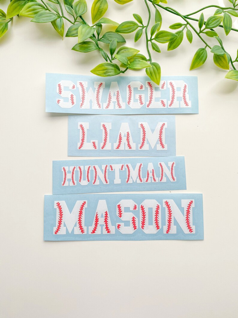 May include: Four blue and white baseball-themed name decals with red stitching. The names are "Swagger", "Liam", "Huntman", and "Mason".