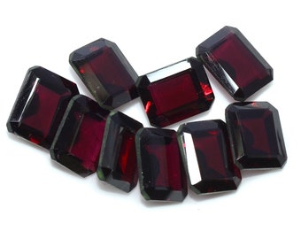 May include: A group of eight dark red gemstone rectangular cut loose stones. The stones are faceted and have a glossy finish.