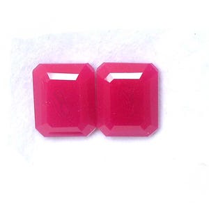 Puede incluir: Dos piedras preciosas de color rosa intenso y vibrante, talladas en forma de esmeralda rectangular. Cada piedra presenta bordes facetados que reflejan la luz, creando una superficie pulida y lisa. Las piedras están colocadas una al lado de otra.
