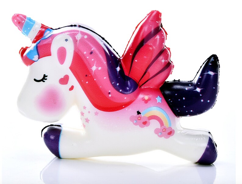 Puede incluir: Un juguete de unicornio blanco con mejillas rosadas, un cuerno a rayas y alas coloridas. Las alas son rojas y rosas con un dise&ntilde;o de estrellas. Un arco&iacute;ris y nubes est&aacute;n en el costado. El unicornio tiene una cola y pezu&ntilde;as moradas.
