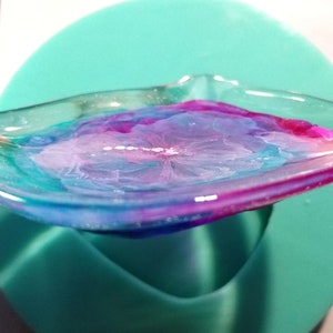 May include: A clear resin tray with a swirling pattern of pink, blue, and white. The tray is sitting on a teal surface.